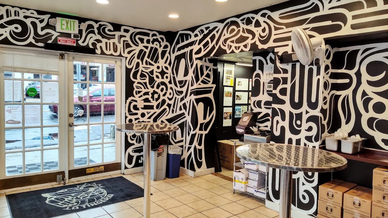 Entrance of La Tingeria Falls Church with the logo on the floor mat and mural on the walls