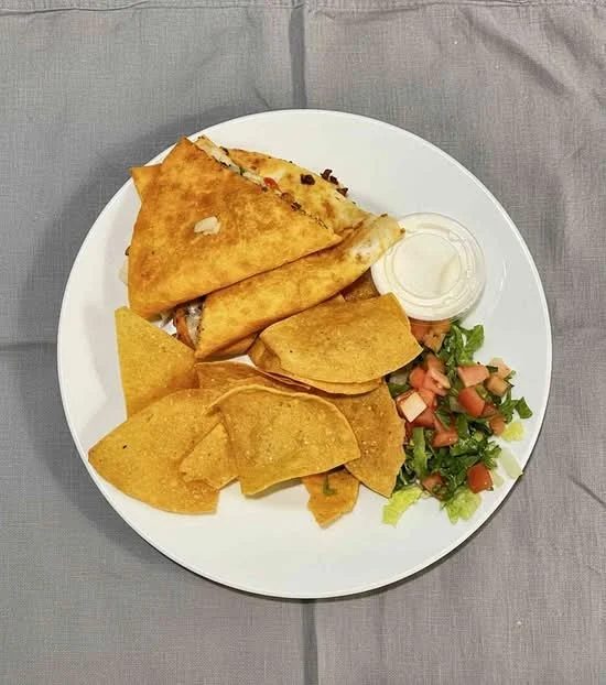 La Tingeria quesadilla plated with tortilla chips, fresh pico de gallo, lettuce, and a side of crema